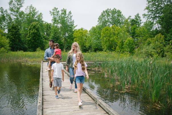 Family of five walking a boardwalk over a marsh at the M.L. Red Trabue Nature Preserve