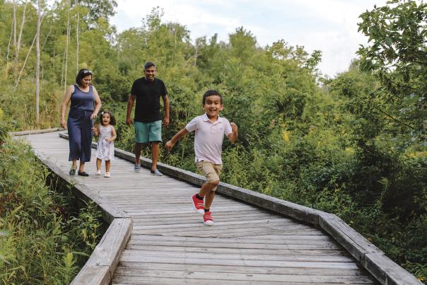 Kid running in front of his family on the boardwalk at Kiwanis Riverway Park