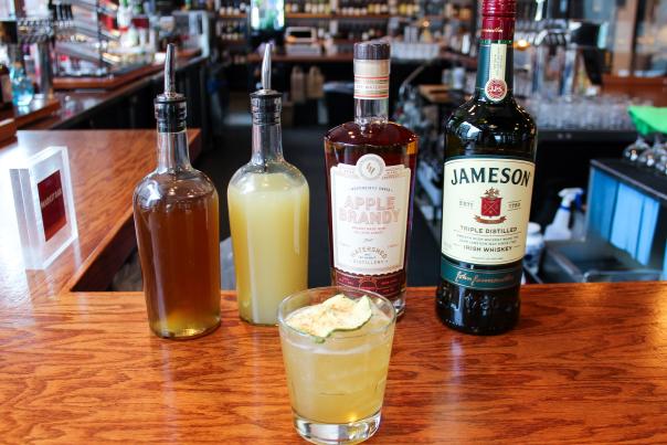 The Dubliner Celtic Cocktail from Market Bar in from of ingredients bottles