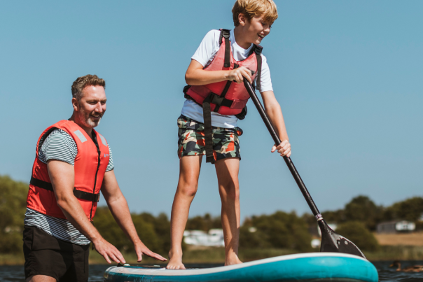 Father helping son to paddle board at Allerthorpe Lakeland Park