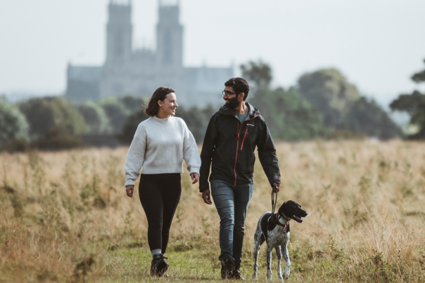 A couple walking their dog on Beverley Westwood with Beverley Minster in the background