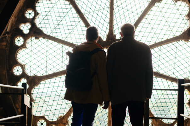 Two people looking out of the huge rose windows on a roof tour of Beverley Minster