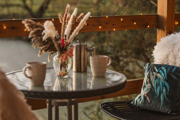 A table and two chairs surrounded by fairy lights, overlooking the water at Kingfisher Lakes in East Yorkshire.