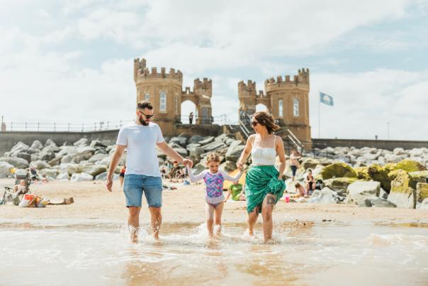 a family paddling in the sea at Withernsea Beach with the pier towers in the background.