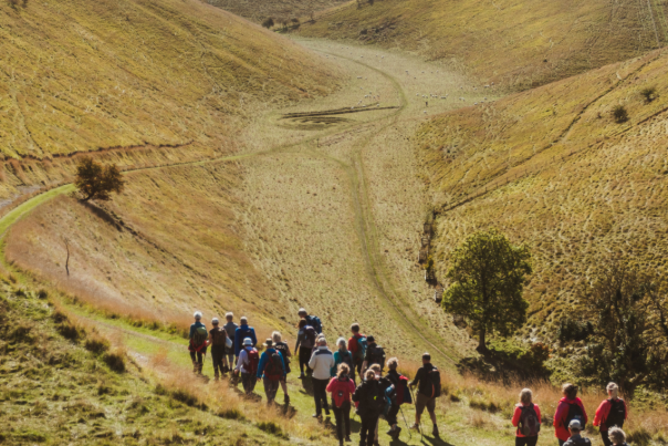 A vast valley in the Yorkshire Wolds with a group of walkers heading towards the bottom