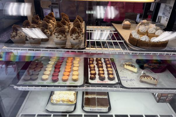 Bakery display case showcasing cupcakes, mini cakes, and other sweet treats.
