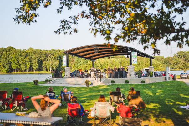 People are sitting in lawn chairs at Freeman Lake listening to a band at the Lawn Party in Elizabethtown, Kentucky