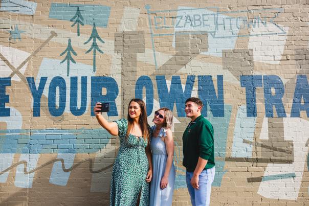 Three friends posing in front of a mural located in Downtown Elizabethtown, KY