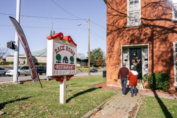 the back home restaurant sign and a couple walking into the restaurant