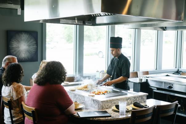diners watching a hibachi chef prepare food in front of them