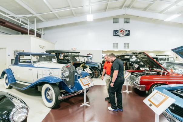 two mean reading a placard in a room of classic cars at swope cars of yesteryear musuem