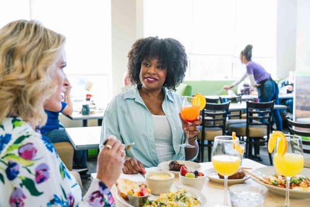 Two women enjoying brunch and conversation in a bright, casual restaurant setting.