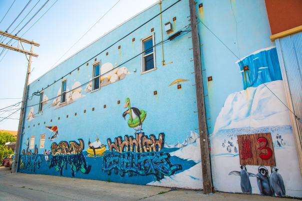 light blue mural featuring penguins on the side of a building
