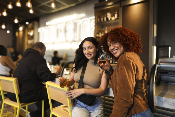 Two friends enjoying drinks and conversation at a stylish Fayetteville bar with warm lighting and a relaxed, modern vibe.