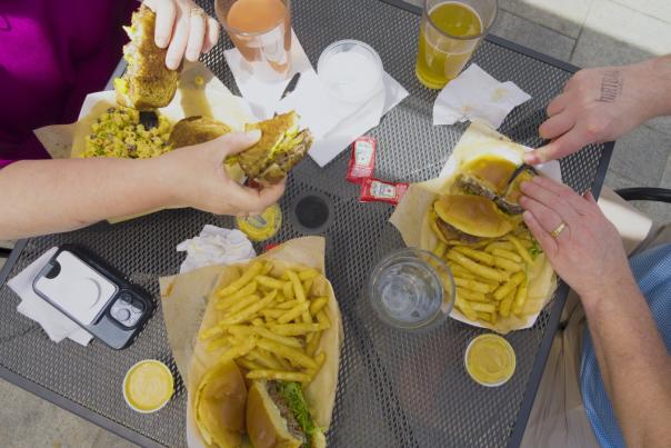 Top view of two people eating burgers and fries at an outdoor table with drinks in Fayetteville NC
.