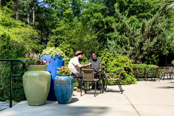 A young couple sitting at a table on the patio outside of Fayetteville's Cape Fear Botanical Garden