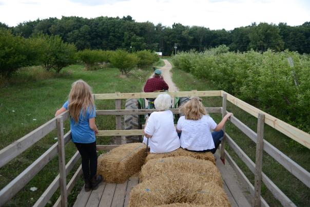 Two women and a girl ride in a wagon through Spicer Orchards.