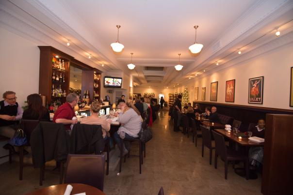 Several people seated at a bar and at inset tables dining at Cork on Saginaw in Flint, MI.