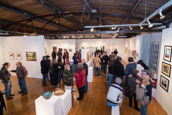 A photo of a crowd of people looking at art and sculptures at the Greater Flint Arts Council during Artwalk.