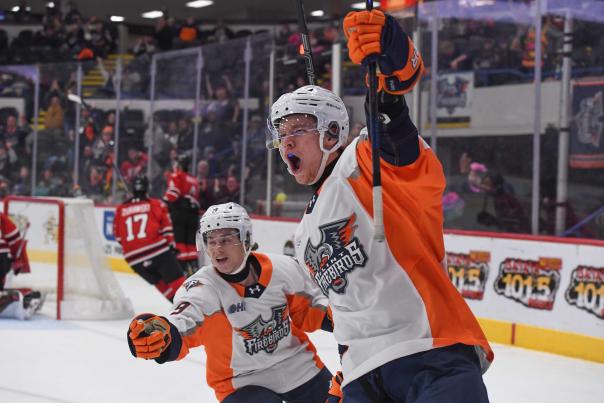 Two Flint Firebirds players celebrate a goal on their home ice.