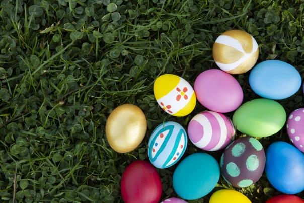An image of several brightly colored Easter eggs lying on grass.