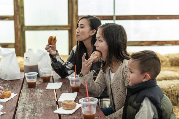 Children sitting around a picnic table eating donuts