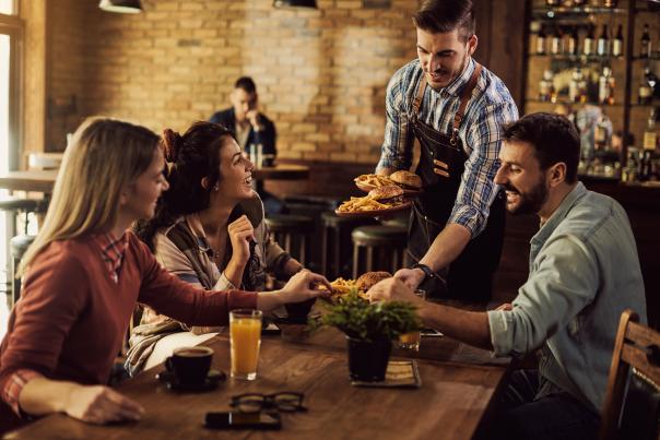 People at a pub being served food by a male server.