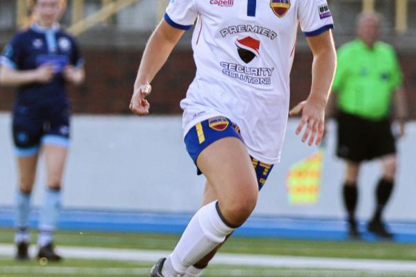 A woman for Flint City AFC soccer club about to kick the ball.