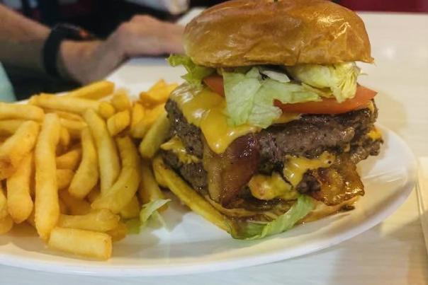 A double cheeseburger and fries on a white plate.