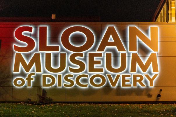 The Sloan Museum of Discovery sign lit up at night.