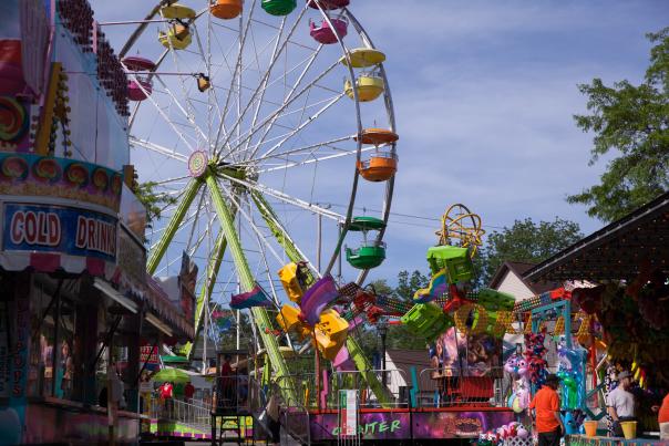 An image of the midway at Swartz Creek Hometown Days with a brightly colored Ferris Wheel at the center.