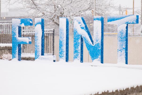 The downtown Flint sign with snow on it.