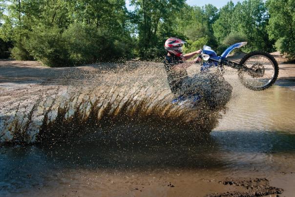 Motorbike rider pops a wheely through a mud hole at the Genesee County Mounds ORV