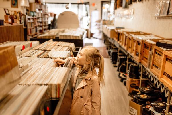 A young girl browses through records in a record store.