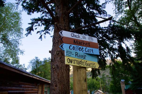 handpainted wayfinding signs that say Check In, Market, Coffee Cart, River, and Overnight Guests
