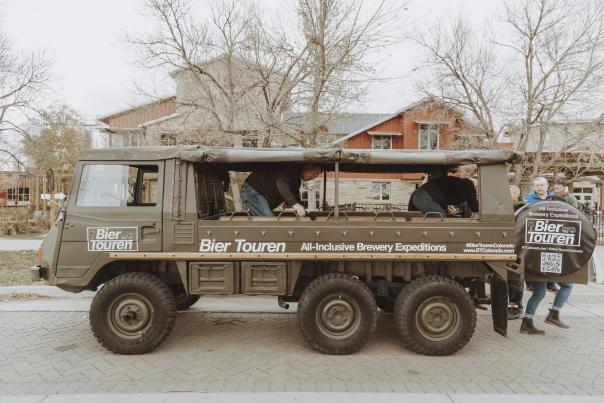 The side of the pinzgauer, a Swiss army vehicle, with Bier Touren branding on the side that says "all inclusive brewery expeditions."