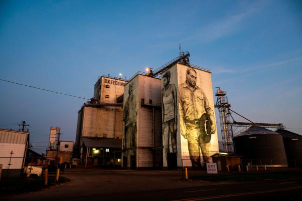 The industrial structures of the O.K. Feed Mill are painted with three larger than life portraits that span the complete vertical length of the structures. Painted by Guido Van Helten in Fort Smith, Arkansas.