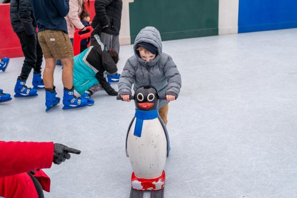 A young boy ice skates with a penguin prop in Fort Smith, Arkansas