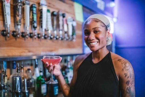 A bartender at Prohibition Bar holds a freshly mixed cocktail behind the bar.