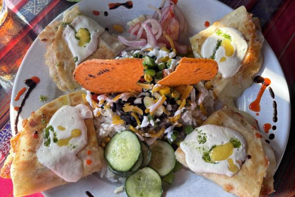 A colorful plate with four quesadillas and beautiful garnish with white sauce, peppers, and meat at Rolando's in Fort Smith, AR.
