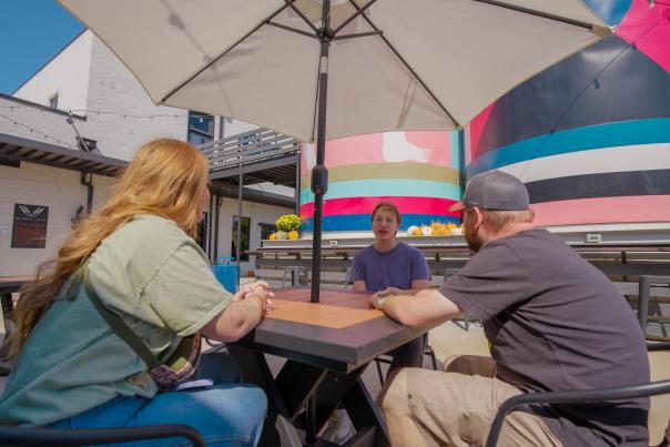A man speaks with two friends while sitting on the patio at the Bakery District in Fort Smith.