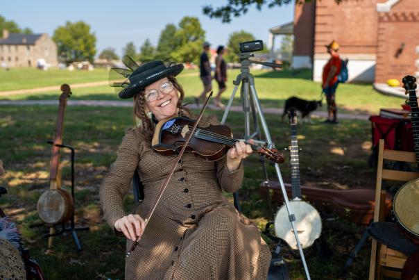 A woman dressed in turn-of-the-century clothes plays a fiddle at the Fort Smith Fall Festival.