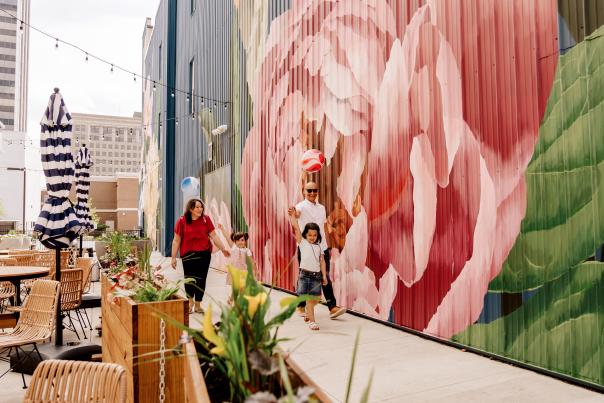 family walking by a restaurant and a mural