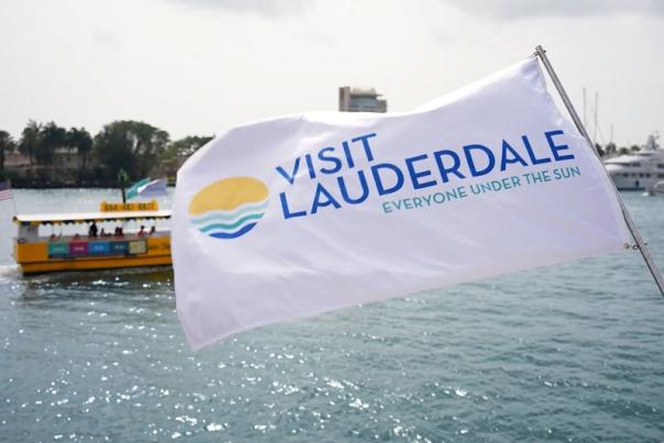 Visit Lauderdale Flag blowing in the wind with the Water Taxi riding behind it.