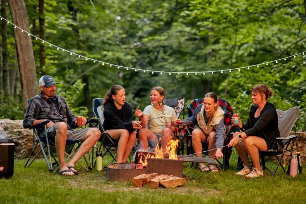 A family sitting around a campfire in a state park, cooking marshmallows.