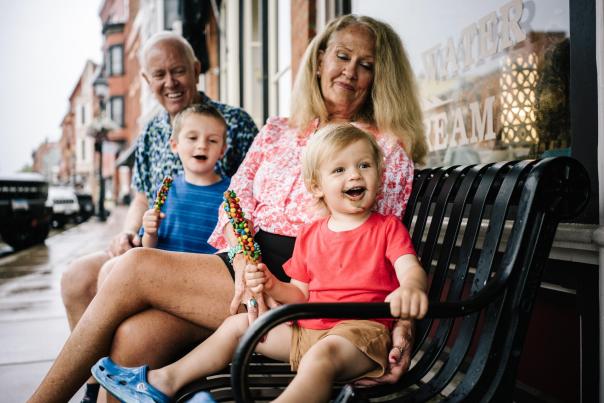 Two adults and two small children sit on a bench on Main Street holding candy.