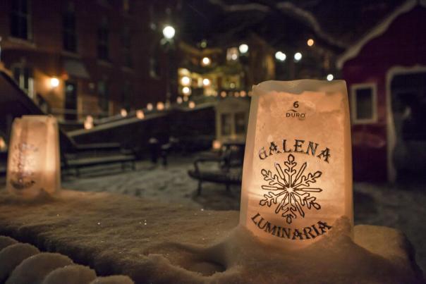 A paper luminary sitting in the snow with "Galena Luminaria" written on it.