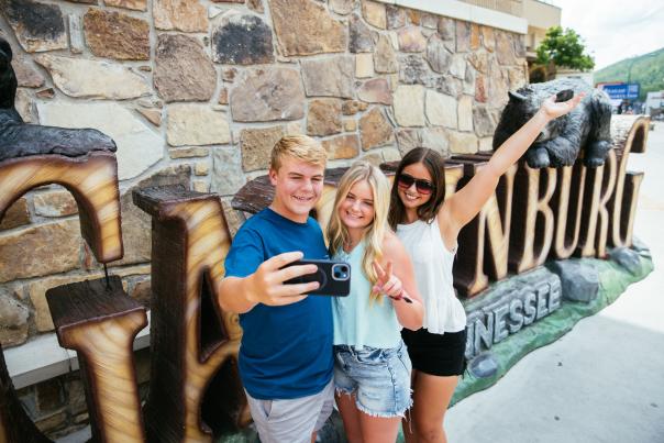 People posing in front of the Downtown Gatlinburg sign