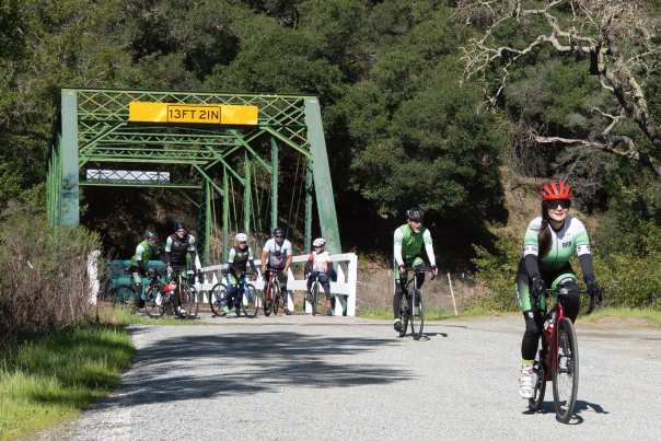 Cyclists riding together during the Tierra Bella Bike Tour in Gilroy, California, on a sunny spring day.