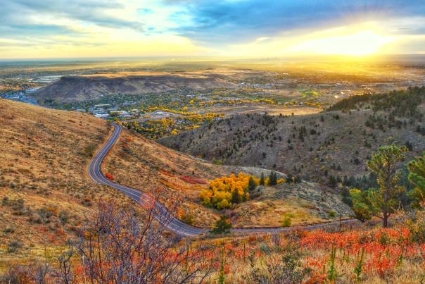 Golden, Colorado, at sunrise, seen from Lookout Mountain Road, with vibrant fall colors of yellow and orange in the foreground.